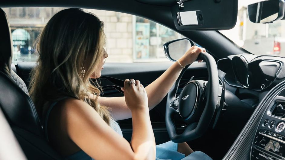 Woman inside car holding sunglasses