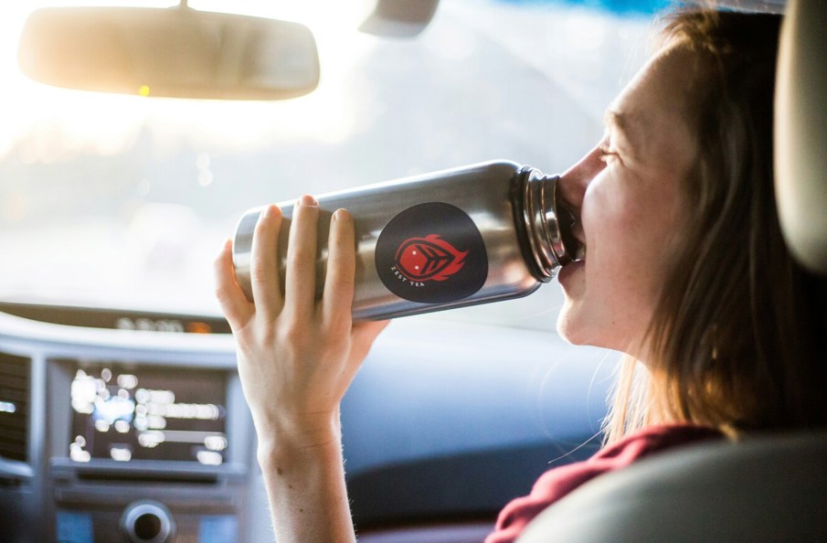 Woman in car drinking from bottle